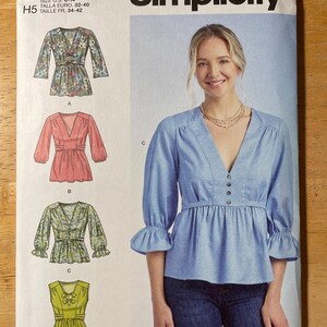 May include: Simplicity sewing pattern S9748 featuring four blouse designs. The pattern includes a blue blouse with a V-neck, button details, and ruffled sleeves. The pattern size is U.S. 6-14.
