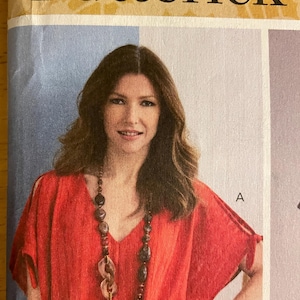 May include: A woman wearing a red V-neck top and a long beaded necklace. The top has short sleeves and a loose fit. The word "Butterick" is printed at the top of the image.