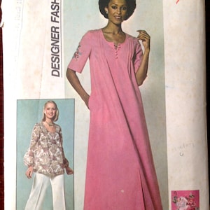 May include: A vintage sewing pattern for a long pink dress with a split front and a white embroidered design on the sleeve. The pattern is for size 14 miss and is from Simplicity pattern number 7970.