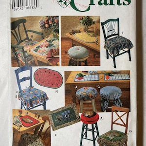 May include: A Simplicity Crafts sewing pattern envelope 9452 featuring illustrations of various home decor items including chair cushions, stools, placemats, and table runners with floral, animal print, and checkered patterns by Donna Lang.
