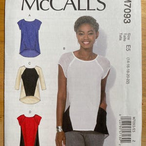 Peut inclure: Un patron de couture McCall's M7093 présentant quatre modèles de hauts. Le patron comprend une femme portant un haut blanc avec des panneaux latéraux noirs. La taille est E5, pour les tailles 14-22.