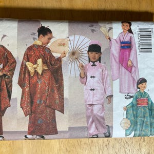May include: A Butterick sewing pattern envelope featuring illustrations of traditional Asian-inspired garments. The cover showcases women and children in kimonos, robes, and a pink suit, holding fans and parasols. The pattern number is 6697.