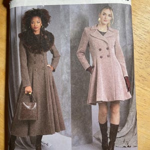 May include: Vogue Patterns sewing pattern V1971. The pattern features two women wearing long coats. The coat on the left is brown with a fur collar, and the coat on the right is pink. The pattern size is HS (6-8-10-12-14).