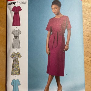 May include: Simplicity sewing pattern S8981, featuring a woman in a burgundy dress with a matching belt. The pattern includes four dress designs, with the text "easy-to-sew" and "SINCE 1927". Sizes U.S. 6-14 are indicated.