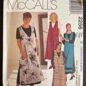 May include: McCall's sewing pattern envelope featuring illustrations of women's dresses. The envelope includes the text "McCall's", "2256", and "Womanstyle". The dresses have various styles, including floral and striped patterns.