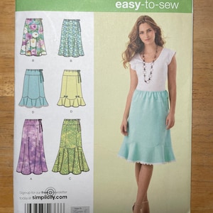 May include: Simplicity easy-to-sew pattern for skirts, size K5. The package features illustrations of various skirt designs, including floral and solid colors. The model is wearing a light blue skirt.