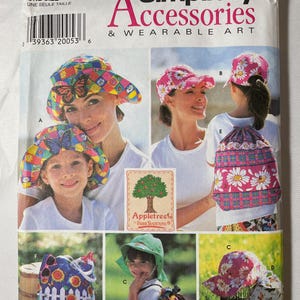 May include: A Simplicity Accessories & Wearable Art sewing pattern envelope, number 7539, featuring illustrations of various hats and drawstring backpacks with floral, butterfly, and plaid patterns, including the Appletree by Fabric Traditions logo.