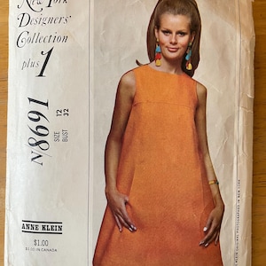 May include: Vintage sewing pattern for a sleeveless dress, featuring a model wearing a bright orange dress with a simple design. The pattern is from the New York Designers' Collection, plus size 12, bust 32. The pattern is titled "New York Designers' Collection plus 1" and is labeled "#8691".