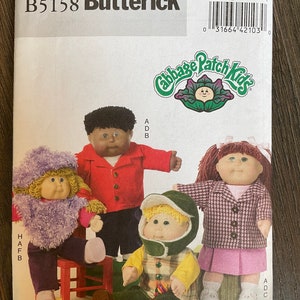 May include: A sewing pattern for Cabbage Patch Kids clothing. The pattern is for a red jacket, a green jacket, a purple jacket, and a pink skirt. The pattern is from Butterick and is number B5158.