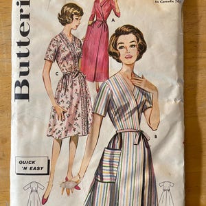 May include: Vintage sewing pattern for a wrap dress with a striped, floral, and solid design. The pattern is from Butterick and is size 14, number 2319. The pattern is for a quick and easy project.