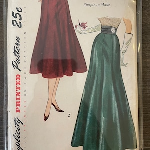 May include: Vintage Simplicity sewing pattern for a skirt. The pattern is for sizes 36 waist and 45 hip. The pattern is printed on a white background with a red and green illustration of a woman wearing the skirt. The pattern is labeled "Simplicity Printed Pattern 25c".