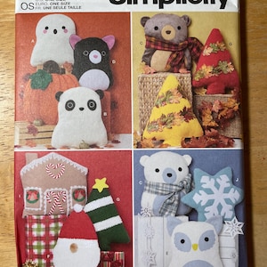 May include: Simplicity sewing pattern S3024 featuring various felt plushie designs. Includes a ghost, panda, bear, owl, and holiday-themed characters like a Santa, Christmas tree, and gingerbread house. The pattern is designed and printed in the USA.
