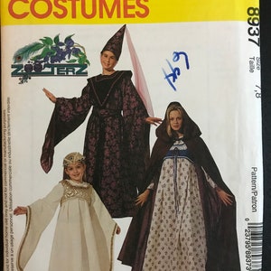 May include: McCall's Costumes sewing pattern for children's costumes. The pattern includes a purple and black hooded dress with a matching hat, a white dress with a gold trim and a crown, and a brown hooded cape with a floral print dress. The pattern number is 8937 and the size is 7-8.