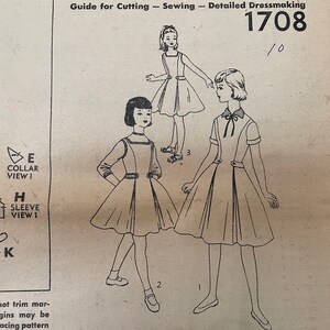 May include: A vintage Simplicity sewing pattern for a dress, featuring three illustrations of girls wearing the dress. The pattern number is 1708. The text "Simplicity primer" and "Guide for Cutting - Sewing - Detailed Dressmaking" is also included.