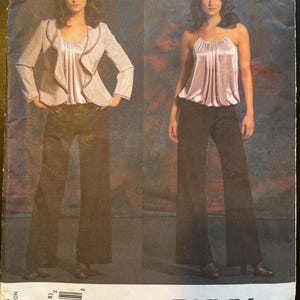 May include: A sewing pattern for a women's top and pants. The pattern is from Donna Karan New York and is for sizes 12-14-16-18. The pattern is for a top with a ruffled neckline and a pair of wide-leg pants.