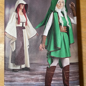 May include: Simplicity pattern 9199 features costume designs. The cover shows two models wearing hooded cloaks and dresses. The pattern includes sizes U.S. 14-22 and is designed and printed in the USA.