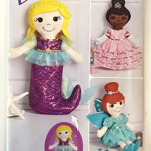 May include: Simplicity sewing pattern S8863 showing three felt doll designs: a mermaid with a purple sequined tail, a princess in a pink dress, and a fairy in a blue dress. The pattern includes instructions for making these fabric dolls.
