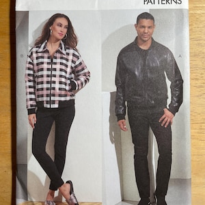 May include: Vogue Patterns sewing pattern V1877. The pattern features two jacket designs. One jacket is a black and white plaid with a zipper closure. The other jacket is a black leather bomber jacket. The pattern size is XN (XLG-XXL-XXXL).