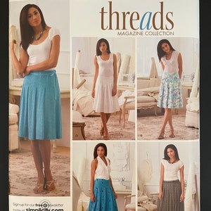 May include: A sewing pattern for four different skirts. The pattern is from Simplicity Threads Magazine Collection and includes sizes H5 6, 8, 10, 12, 14, EUR. 32-40, FR. 34-42. The pattern shows four different women wearing the skirts in different colors and patterns.