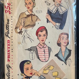 May include: Vintage Simplicity printed sewing pattern featuring illustrations of women's fashion designs. The pattern includes various collar and accessory styles, with the price of 35 cents printed on the cover. The pattern is labeled as "One Size."
