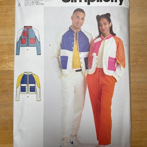 May include: Simplicity sewing pattern S9896 showing jacket designs. The pattern includes illustrations of jackets in blue, yellow, and pink colour schemes. The text "Designed and printed in USA" is visible.