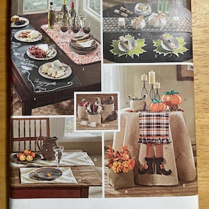 May include: Simplicity sewing pattern with table setting designs. The image displays table decor ideas, including placemats, table runners, and decorative elements like pumpkins and candles. The pattern includes text and is designed and printed in the USA.