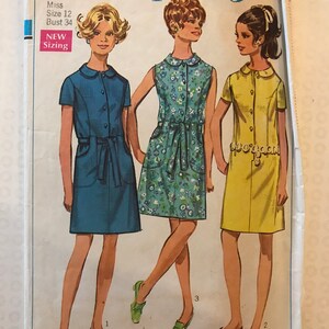 May include: Simplicity sewing pattern number 8029 for a dress. The pattern is for a miss, size 12, bust 34. The pattern shows three different styles of dresses, one in blue, one in floral print, and one in yellow.