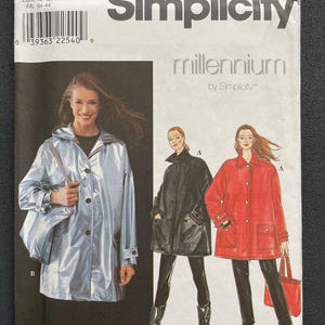 May include: Simplicity pattern 8536 for a coat, featuring three models wearing different versions of the coat. The model on the left is wearing a silver coat, the model in the middle is wearing a black coat, and the model on the right is wearing a red coat. The pattern is for sizes XS, S, and M.