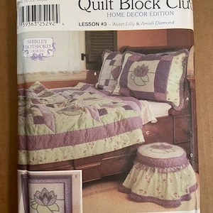 May include: Simplicity Quilt Block Club Home Decor Edition Lesson #3 - Water Lilly & Amish Diamond sewing pattern featuring a purple and green quilt, pillows, and footstool.