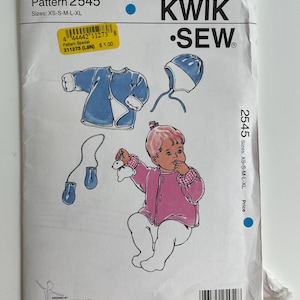 May include: A Kwik Sew pattern envelope 2545 for infant clothing in sizes XS-S-M-L-XL. The white paper envelope features illustrations of a blue jacket, a blue bonnet, blue mittens, and a child wearing a pink jacket with a white rabbit toy.