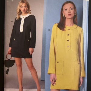 May include: Vogue Patterns V1844 sewing pattern featuring two mini-dress designs. One dress is black with white trim and gold buttons, the other is yellow with matching buttons and pockets. The pattern includes sizes 8-16.