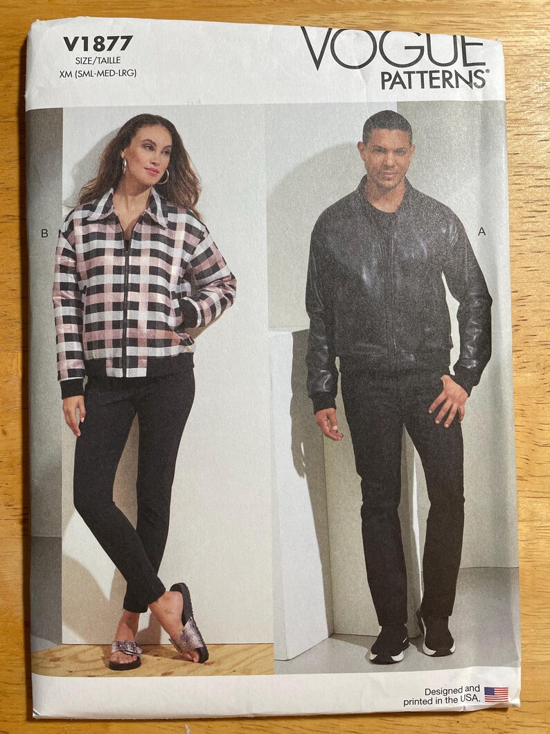 May include: Vogue Patterns sewing pattern V1877. The pattern features two models wearing a jacket and pants. The jacket on the left is a black, white, and pink plaid. The jacket on the right is black. The pattern size is XM (SML-MED-LRG).
