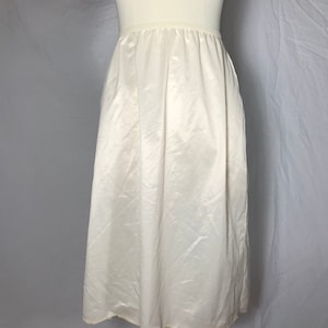 May include: A white satin slip skirt with a lace trim. The skirt is on a white mannequin.