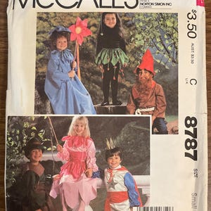 May include: A vintage McCall's sewing pattern showing children in costumes. The costumes include a blue gown, a black top with a green skirt, a gnome, a pink dress, and a patriotic outfit. The pattern number is 8787, size small.