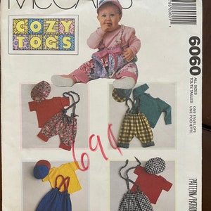 May include: A sewing pattern for making baby clothes. The pattern includes instructions for making a variety of outfits, including a pair of overalls, a shirt, and a hat. The pattern is from McCall's and is called "Cozy Togs".