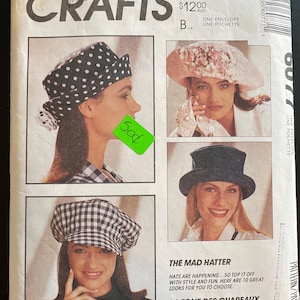 May include: McCall's Crafts pattern envelope showing women modelling different hats. Text includes "The Mad Hatter" and "La Folie Des Chapeaux". A green price sticker is visible on the front of the envelope.