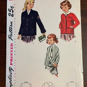 Peut inclure: Un patron de couture vintage Simplicity pour une veste d'enfant. Le patron est pour la taille 7 et coûte 25 cents. Le patron montre trois styles de vestes différents : une veste bleu marine avec une poche et un écusson, une veste rouge avec une poche et une veste rayée avec une poche.