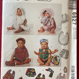 May include: A sewing pattern for baby clothes. The pattern includes four different designs for bibs and bonnets. The pattern is called McCall's 6627 and is for one envelope. The pattern is printed on white paper with black text.
