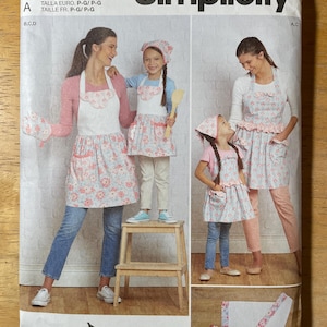 Peut inclure: Patron de couture Simplicity S9565. Le patron propose des tabliers à imprimé floral et volants. L'image montre une mère et sa fille portant les tabliers. Le texte "easy-to-sew" est visible.