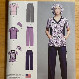 May include: Simplicity sewing pattern 1020 AA for scrubs. The pattern includes a scrub top, pants, and cap. The scrub top has a V-neck and pockets. The pattern is printed in the USA and includes sizes 10-18.