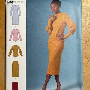 May include: Simplicity sewing pattern S8982 featuring a woman in a mustard-colored knit outfit. The pattern includes options for a dress, top, and skirt. The cover also shows illustrations of the garment options. The pattern is marked "easy-to-sew."