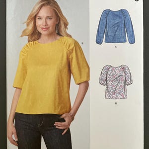 May include: New Look sewing pattern N6708 for a top with gathered shoulders and sleeves. The envelope displays a yellow top with elbow-length sleeves and two technical illustrations showing variations A and B, including a floral print option.