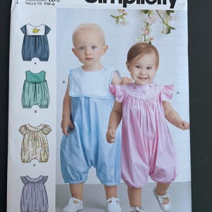 May include: Simplicity pattern 9484 for baby rompers. The image shows illustrations of different romper styles, including a blue romper with a duck design and a pink romper with frilly sleeves. Designed and printed in the USA.
