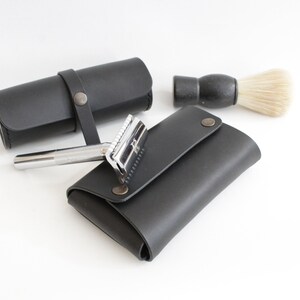 May include: A black leather shaving kit with a safety razor, a shaving brush, and a separate pouch for the razor.