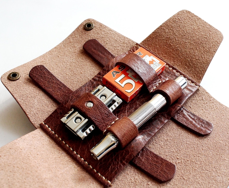 May include: A brown leather travel case with a razor, blades, and a shaving brush. The case has a flap that closes with a snap.