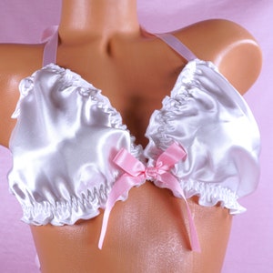 May include: White satin lingerie top with a pink bow and ruffled trim.