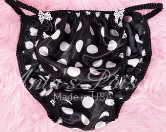 May include: Black satin underwear with white polka dots and black trim. The underwear has a bow on each side. "Anita's Pois" and "Made in USA" are printed on the front.
