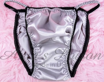May include: Silver satin underwear with black trim and adjustable straps. The underwear is made in the USA.