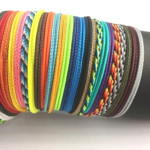 May include: A stack of colorful braided cords, including black, white, red, orange, yellow, green, blue, purple, and grey.