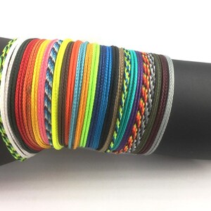 May include: A stack of colorful braided bracelets in various colors, including red, orange, yellow, green, blue, purple, and black.